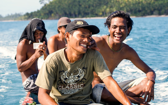 Mentawai youth in a dugout canoe, laughing